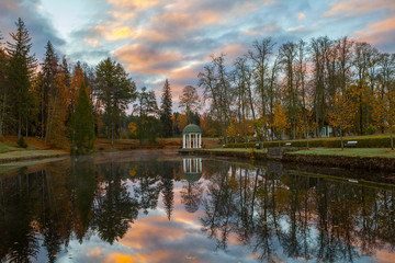 Autumn park around a pond with a rotunda. October fall time.