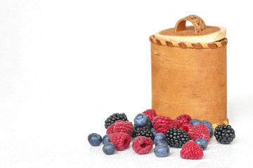 Blueberries, raspberries and blackberries near birch bark basket 