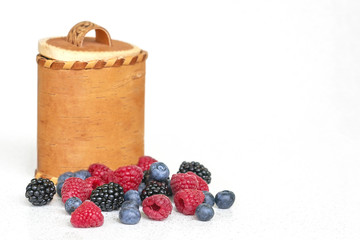 Blueberries, raspberries and blackberries near birch bark basket 