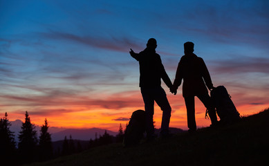 Silhouettes of loving couple enjoying sunset while hiking mountains together copyspace love people affection romance nature landscape travelling sky