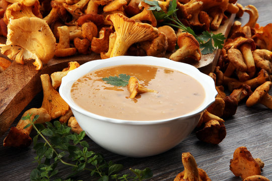 Mushroom cream soup with fresh chanterelles and herbs on a rustic background. Autumn concept.