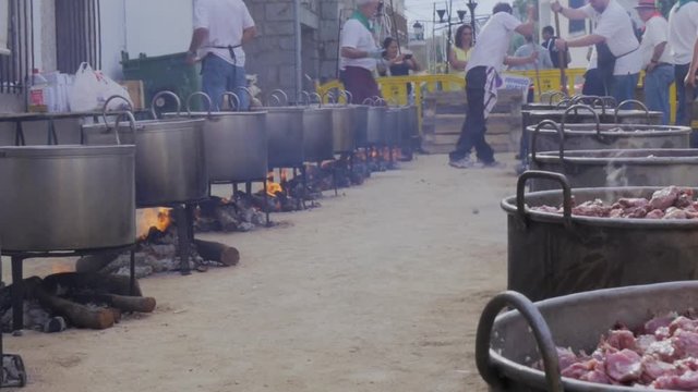Men stirring meat cauldron on fire in popular food