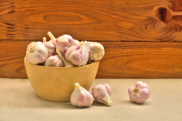 A bowl with garlic on a wooden background