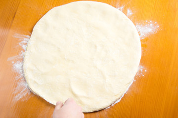 Male baker spreading dough for making pizza