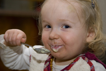 Kleines Mädchen isst fröhlich ihren Pudding