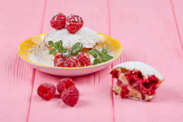 Raspberry muffin. Homemade baked muffin with fresh berries, mint on plate on pink wooden background. Top view.