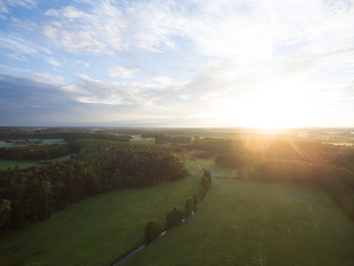 
Aerial view of a beautiful sunset over forest landscape with green fields