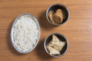 Rice, samosas and onion bhaji on a wooden background 