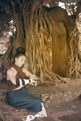 Pretty Asian woman draping in Thai ancient warriors at Gate of time of Wat Phra Ngam in Ayutthaya Historical Park ,Thailand.