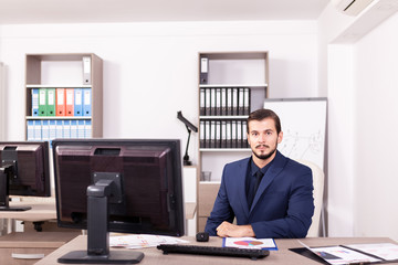 Businessman in suit working in his office. Business and corporate. Image of young succesful entrepreneur at his work place.