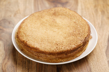 homemade blini stack on plate on wood table