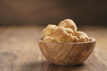 profiteroles in olive bowl on wooden table