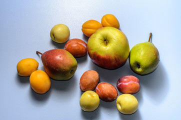 Summer fruits: apples, pears, apricots, plums on a blue table