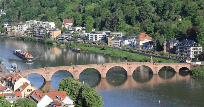 Dry-cargo ship with containers floating along the Neckar River beside the Carl Theodor Old Bridge in Heidelberg, Baden-Wurttemberg,  Germany
