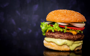 Delicious handmade burger on dark background. Close view