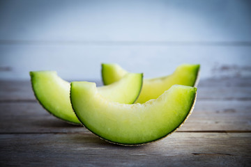Slices of fresh organic melon isolated on wooden background