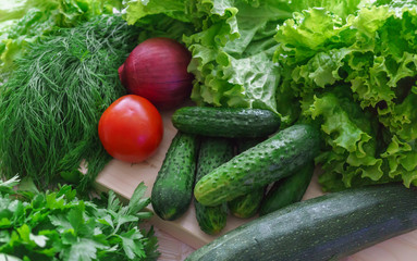 Beautiful green greens with cucumbers and red tomato and onions.