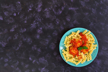 Meatballs with fusilli on dark background.