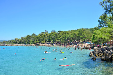 People are swimming in a turquoise sea in Incekum Beach, Marmaris.
