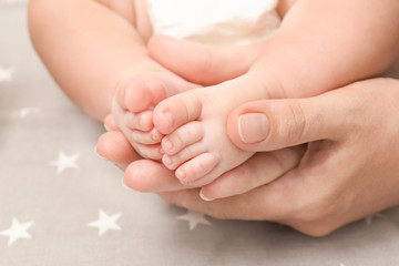 Fototapeta na wymiar Mother hands holding little baby legs, closeup
