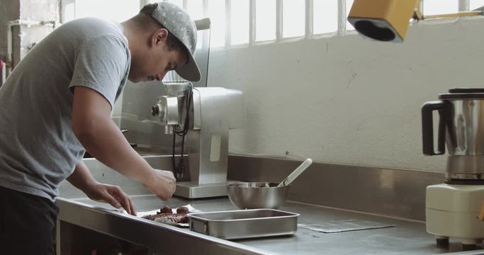immxed race man makes a chocolate sweets in industrial kitchen.