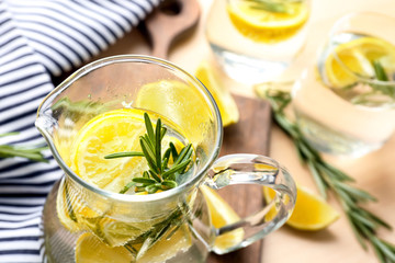Jug of fresh lemonade with rosemary on table, close up
