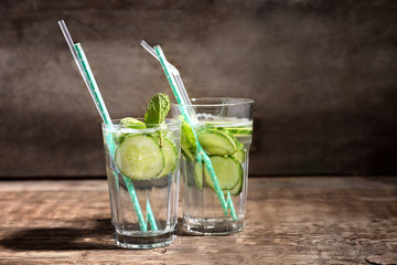 Glasses of fresh cucumber lemonade on wooden background