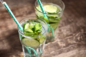 Glasses of fresh cucumber lemonade on wooden background