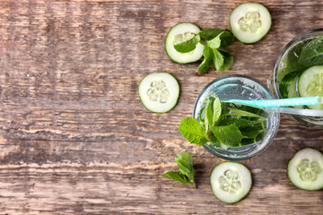 Glass of fresh cucumber lemonade on wooden background