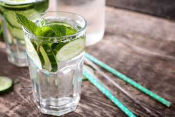 Glass of fresh cucumber lemonade on wooden background