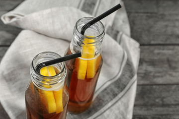 Bottles of fresh black tea lemonade on wooden background
