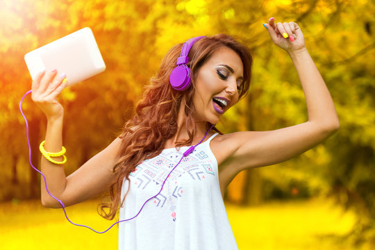 Young happy woman listening music in park