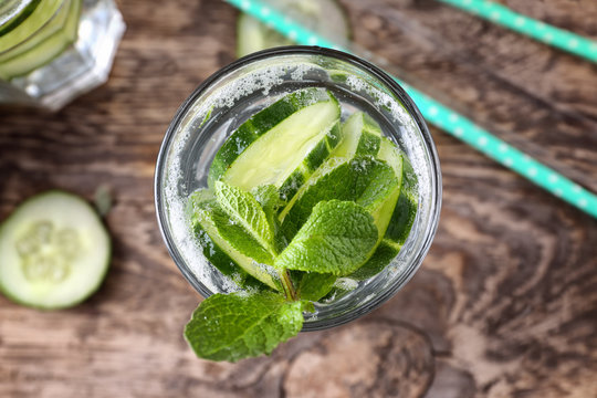 Glass of fresh cucumber lemonade on wooden background, close up