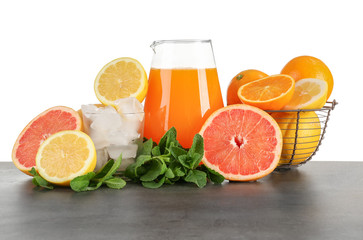 Jug of fresh lemonade with citrus fruits on white background