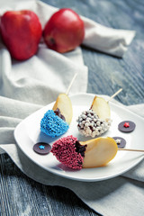Plate with pieces of candied apple and napkin on wooden table