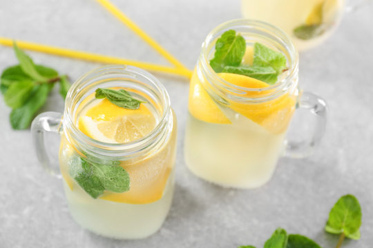 Mason jars of fresh lemonade on grey background