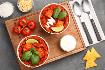Two bowls with delicious chili turkey on wooden board