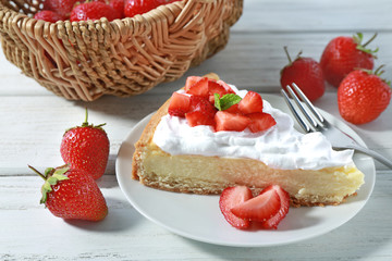 Piece of cake with cream and strawberries on plate