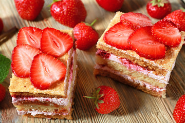 Two pieces of cake with strawberries on wooden table