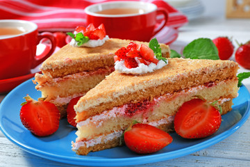 Two pieces of cake with strawberries on blue plate