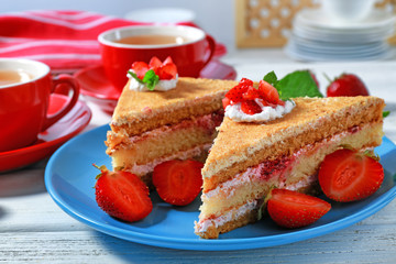 Two pieces of cake with strawberries on blue plate