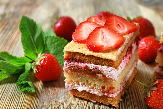 Piece of cake with strawberries on wooden table