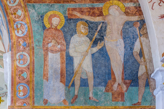 The crucifixion, a medieval fresco with an ultramarine background. Longinus holds the holy lance. Virgin Mary stands beside the cross. 