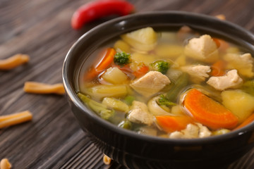 Bowl with delicious turkey soup on wooden background