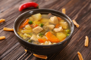 Bowl with delicious turkey soup on wooden background