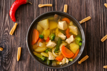 Bowl with delicious turkey soup on wooden background