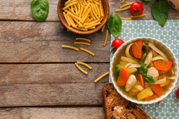 Bowl with delicious turkey soup on wooden background