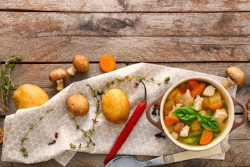 Casserole with delicious turkey soup on wooden background