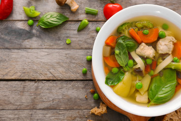Bowl with delicious turkey soup on wooden background