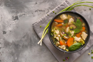Black bowl with delicious turkey soup on grey background